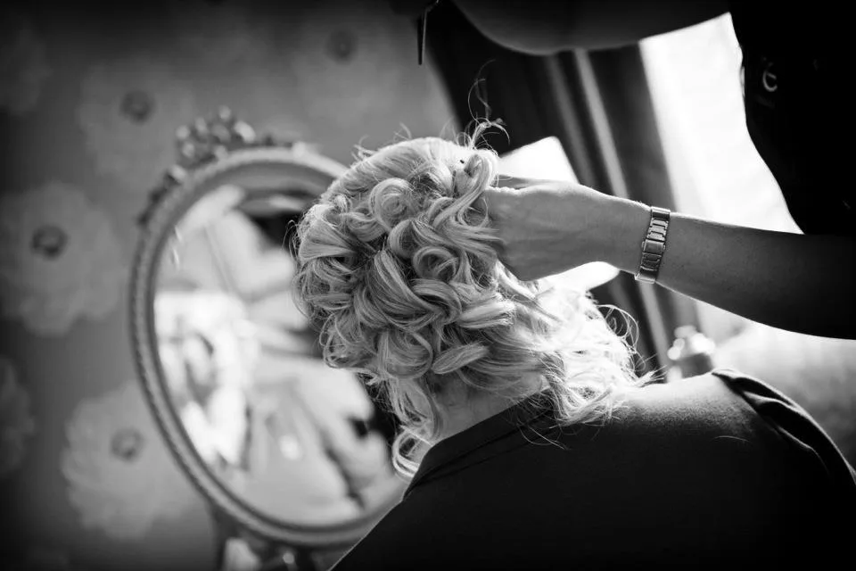 Finishing soft curls in the mirror, in black and white